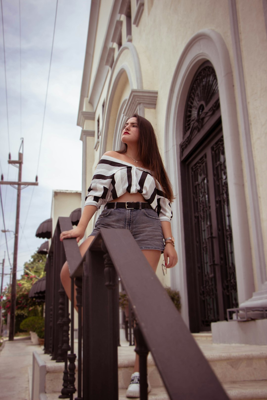 woman in white and black stripe shirt and blue denim jeans standing on stairs