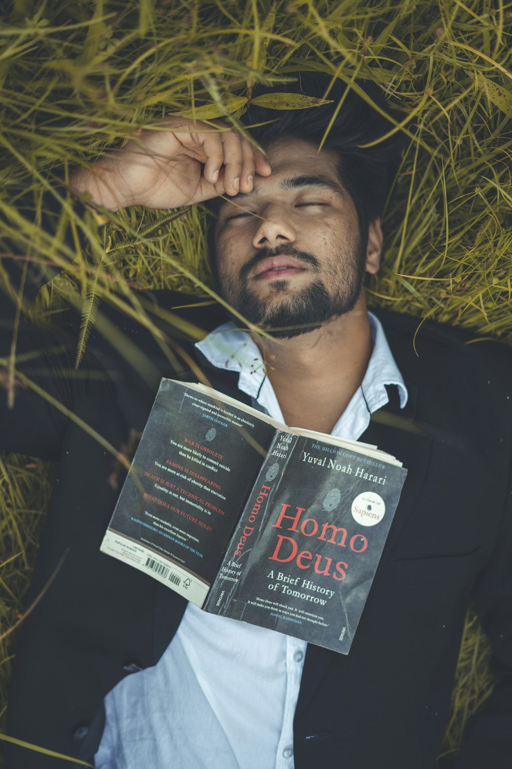 man in black suit jacket holding black book