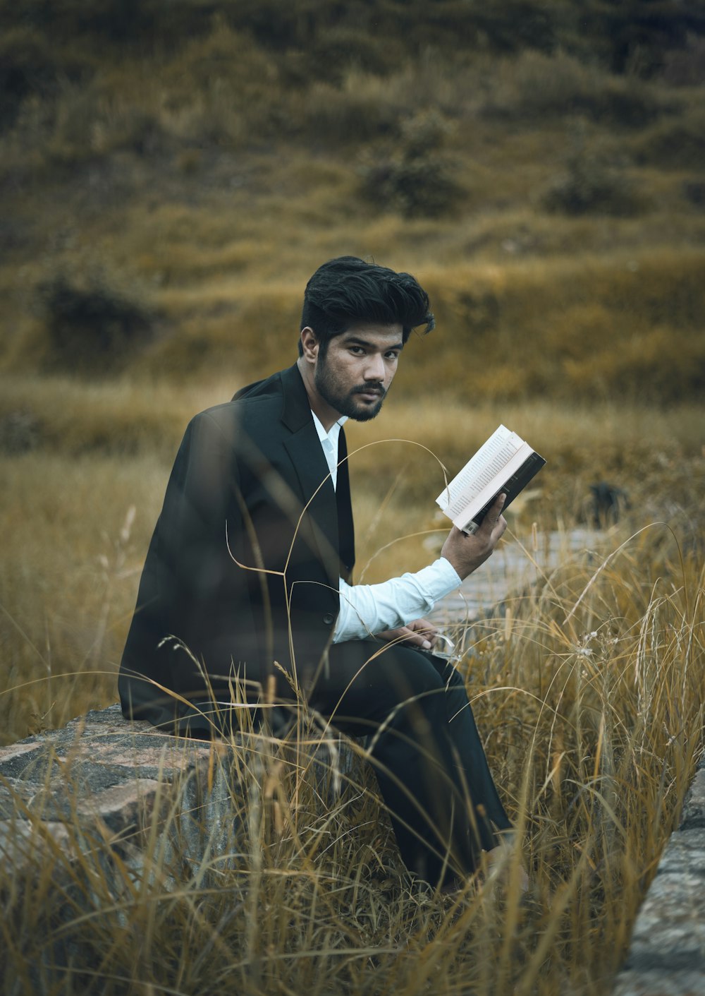 man in black suit holding book