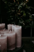 A set of elegant candles arranged on a dark wooden tray with subtle floral accents.