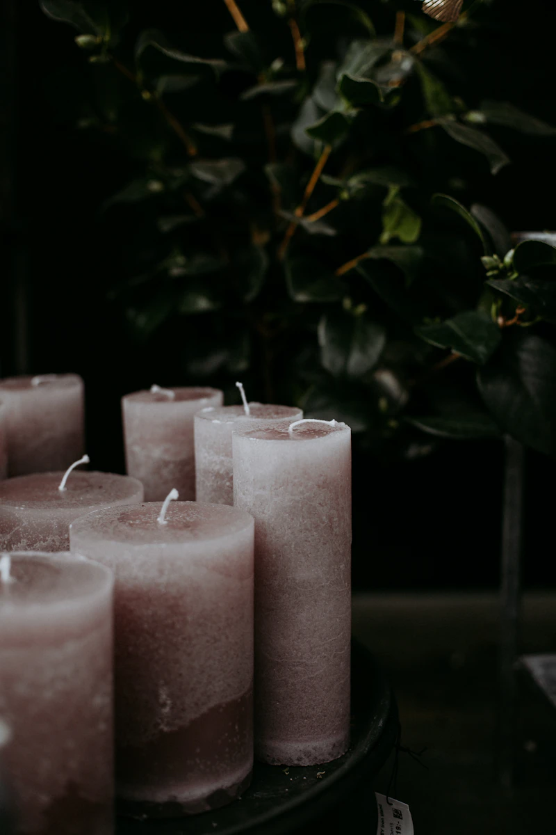 Three pink pillar candles with greenery
