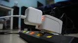 Close-up of a power strip with multiple plugs, showing a warning sign about overloading.