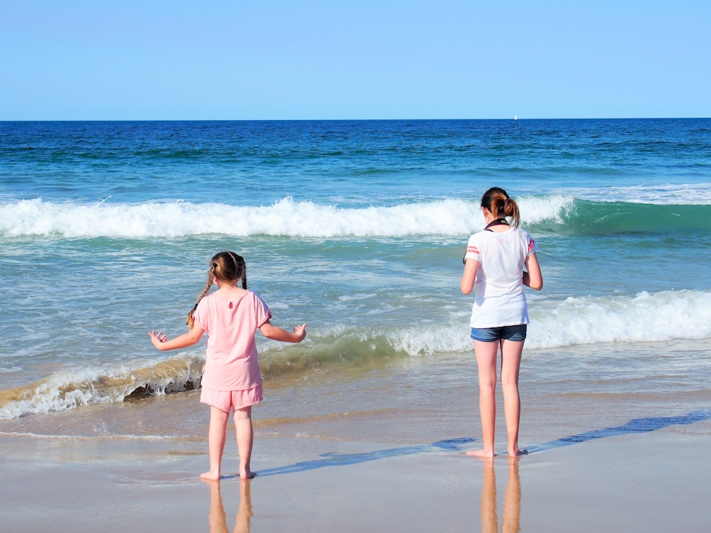 2 girls walking on beach during daytime
