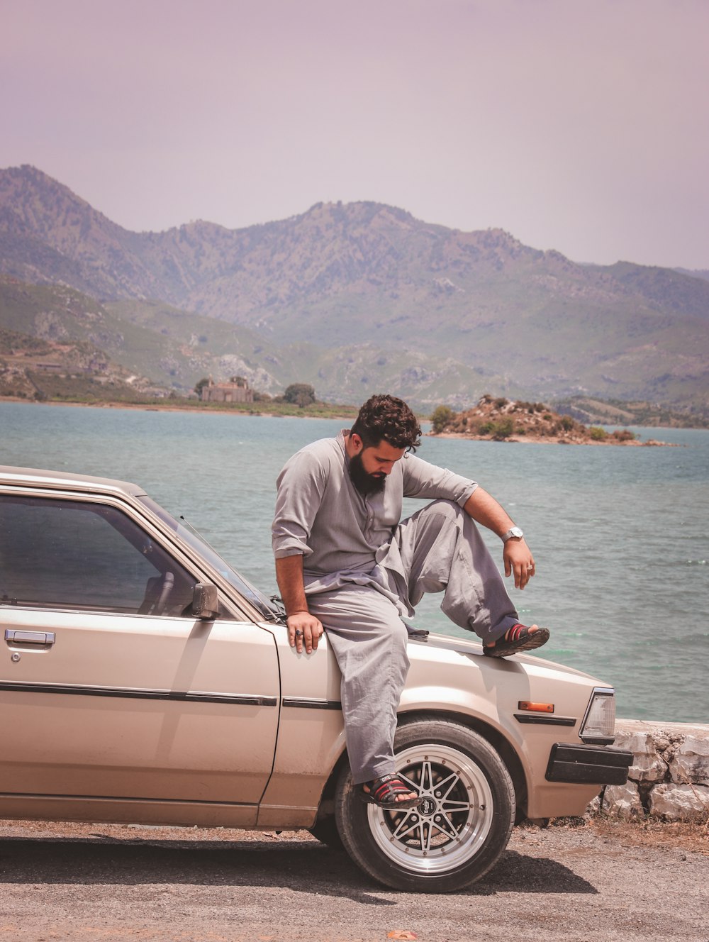 man in gray t-shirt sitting on white car