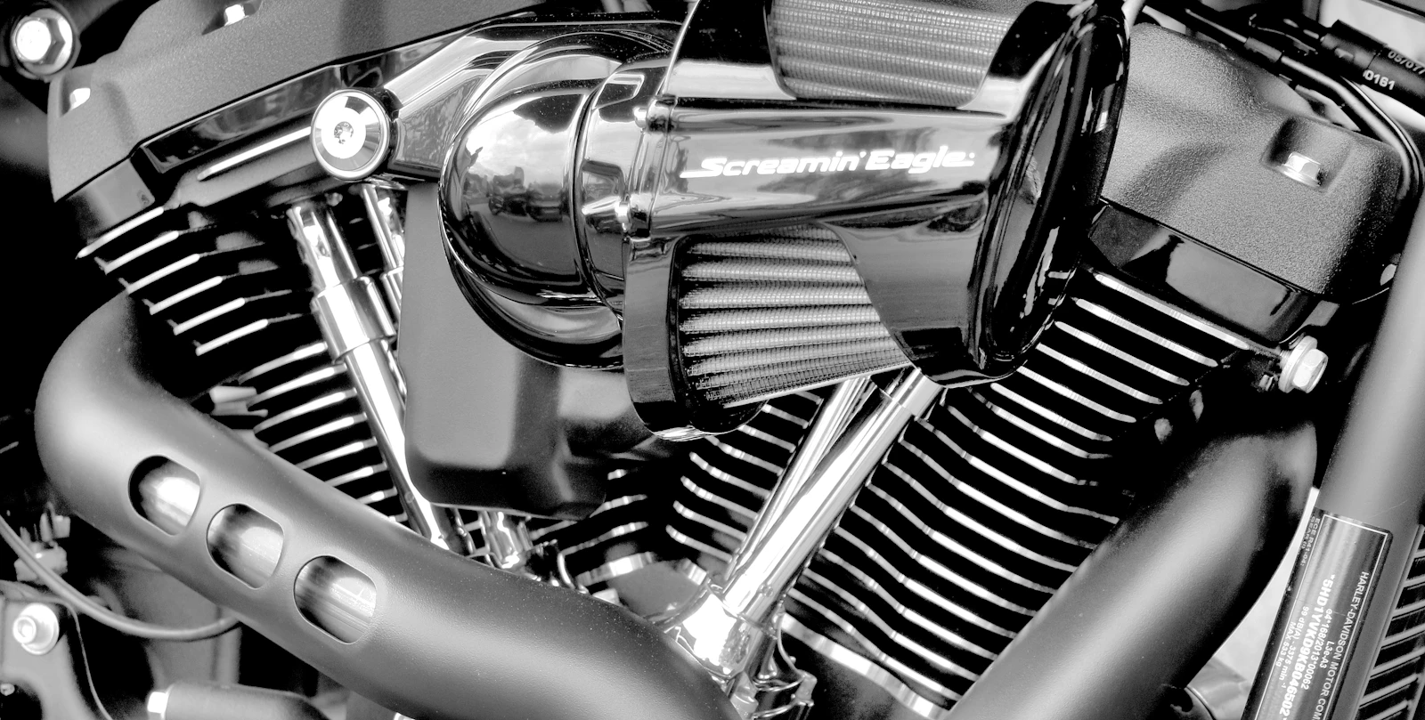 Black-and-white close-up of a Harley-Davidson V-twin with a high-flow air cleaner and chrome pipes, the fuel-injected motor that goes on the dyno at Kings North Coast Customs