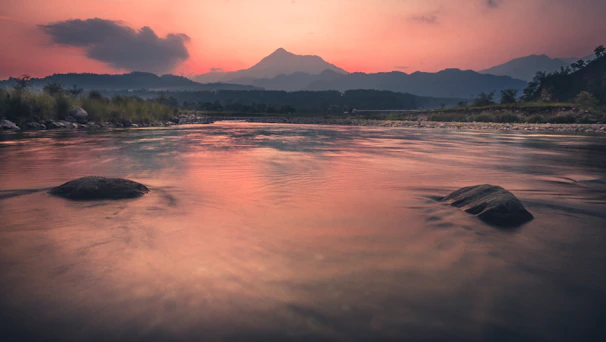 Serene spa scene with lit candles, smooth stones, and flowing mountain water at sunset