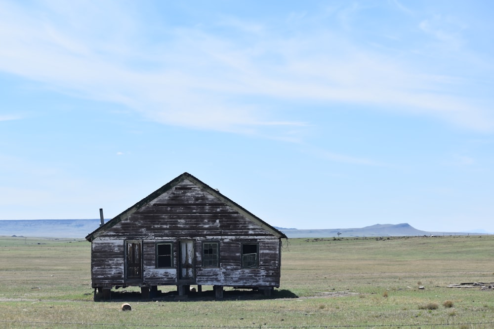 brown wooden house on green grass field under blue sky during daytime