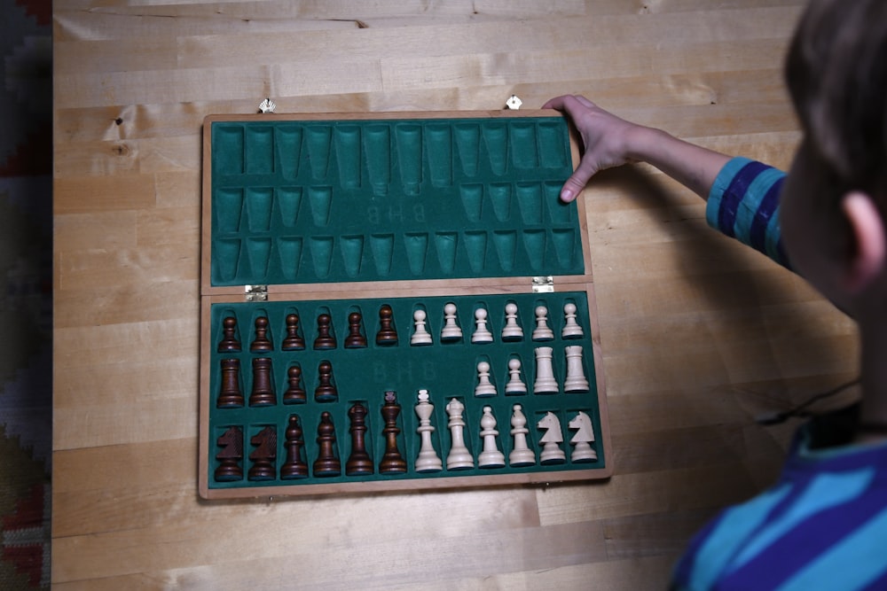 person holding green and black chess board
