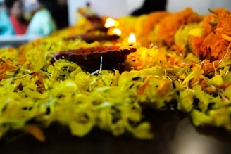 A beautifully arranged Vishu Kani setup featuring an uruli filled with fruits, bright kanikkonna flowers, and a shimmering valkannadi mirror reflecting golden sunlight.