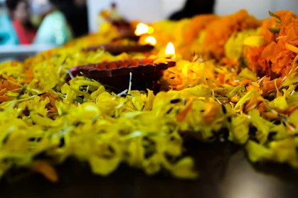 Golden camphor blocks glowing softly on a wooden plate surrounded by marigold flowers.