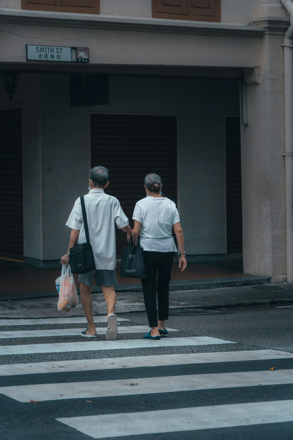 man in white t-shirt and black pants holding hands with woman in white dress