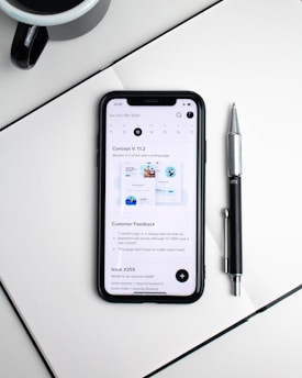 An open notebook with handwritten saving tips next to a cup of coffee and a smartphone showing deals