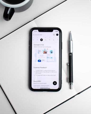 A close-up of hands writing notes beside a cup of coffee and a smartphone.