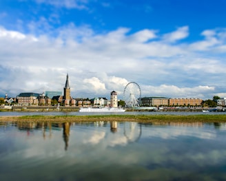 white ferris wheel near body of water under blue sky during daytime