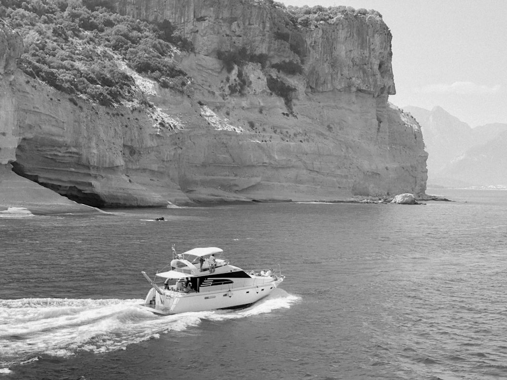 white and black motorboat on sea near brown rocky mountain during daytime