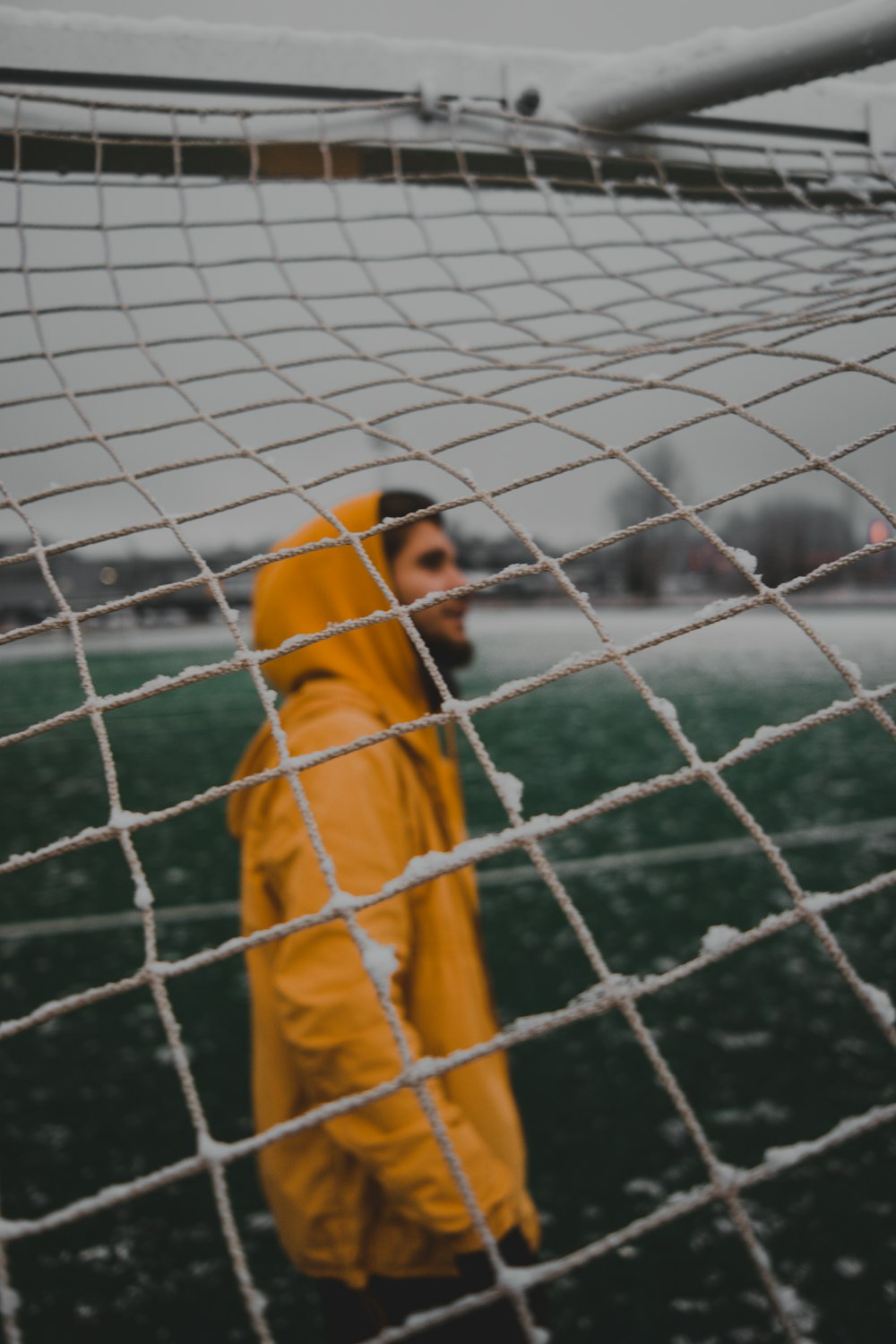 a man in a yellow jacket standing in front of a net