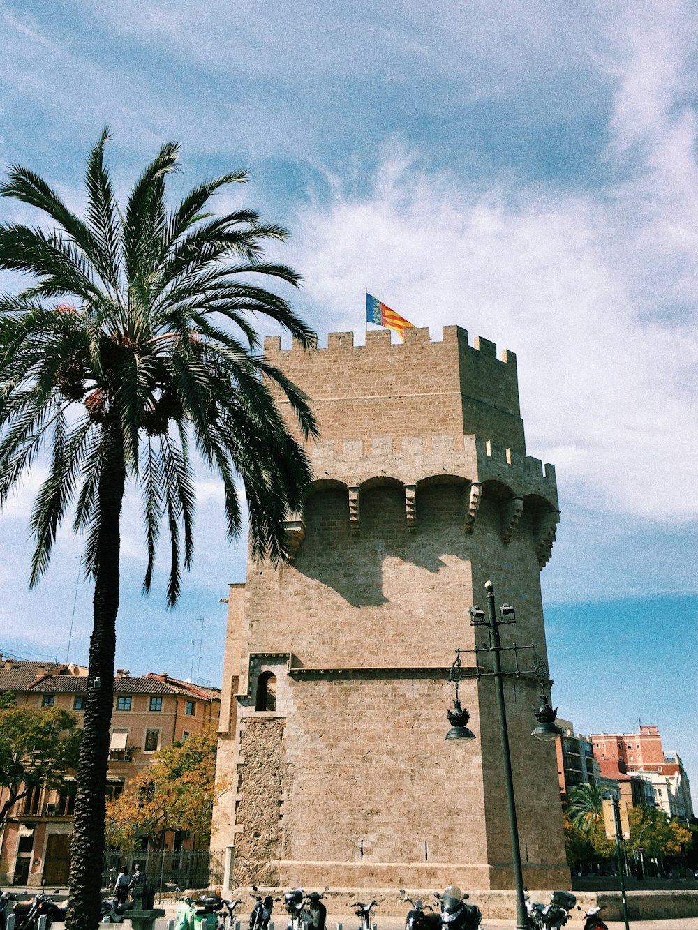 Bâtiment en béton gris près de Palmtree sous un ciel nuageux pendant la journée