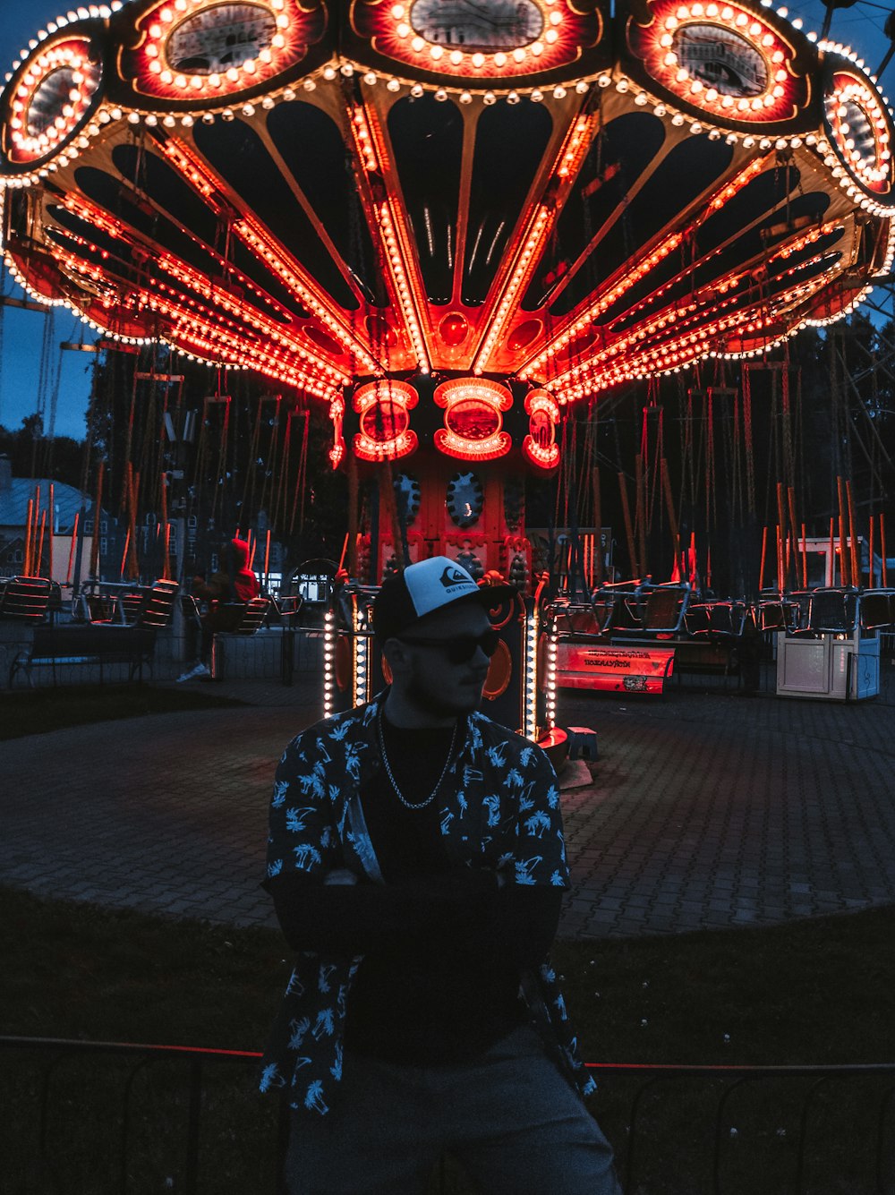 man in black and white floral long sleeve shirt wearing black hat standing near red and