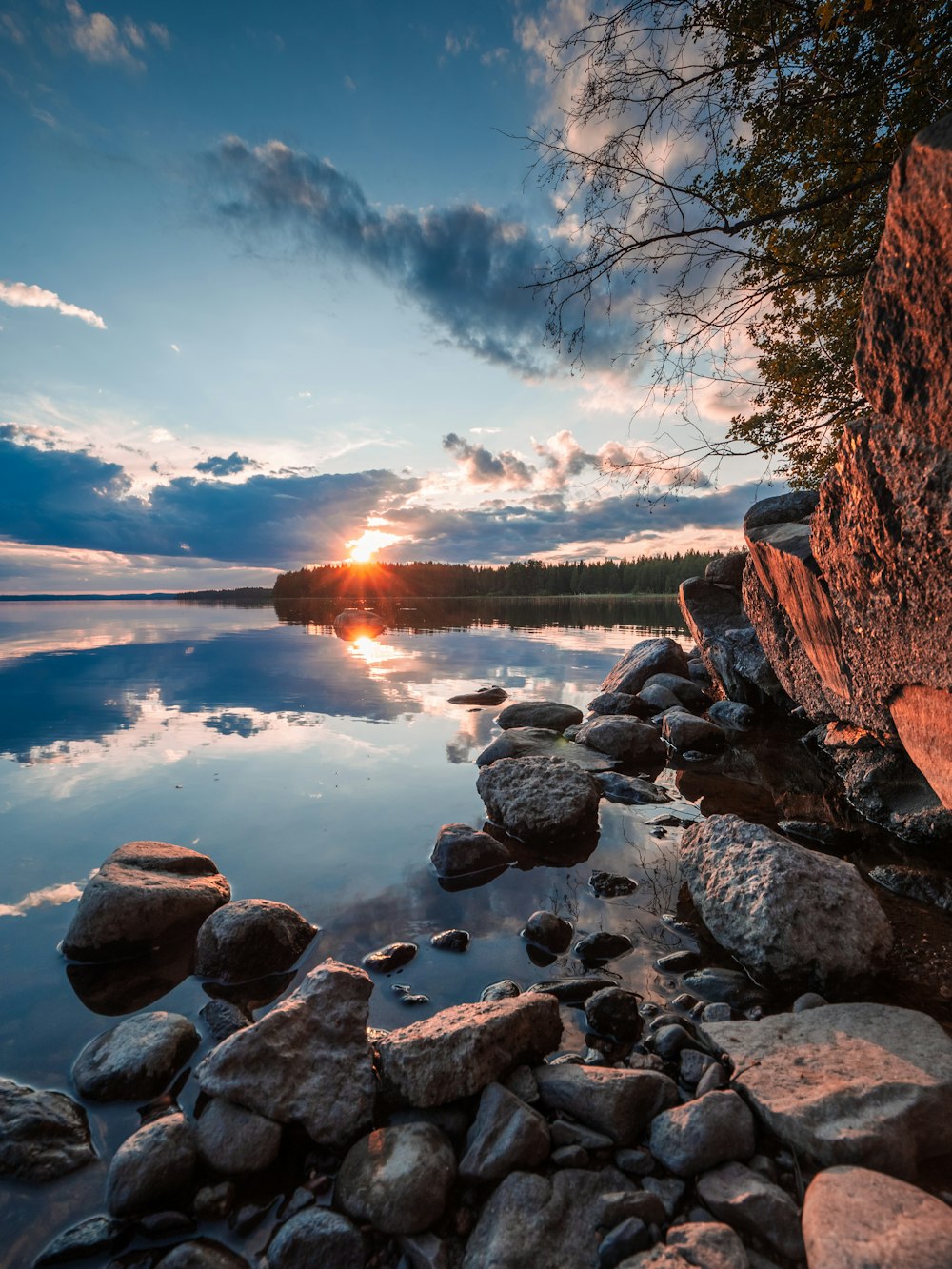 gray rocks near body of water during sunset