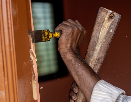 A friendly handyman in a tool belt fixing a wooden door frame in a cozy San Francisco home.