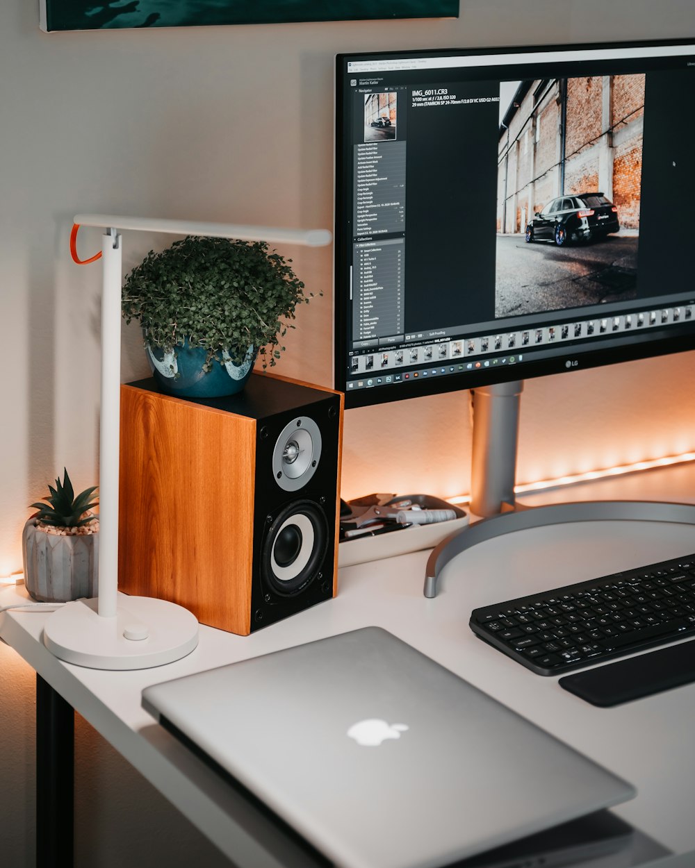 silver macbook beside black flat screen computer monitor and black computer keyboard on white wooden desk