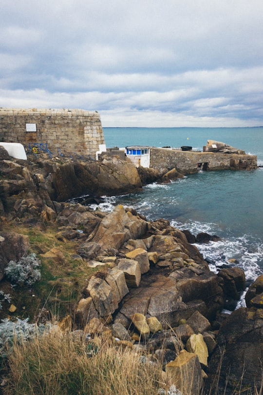 brown concrete building on brown rock formation near body of water during daytime in James Joyce Tower & Museum Ireland