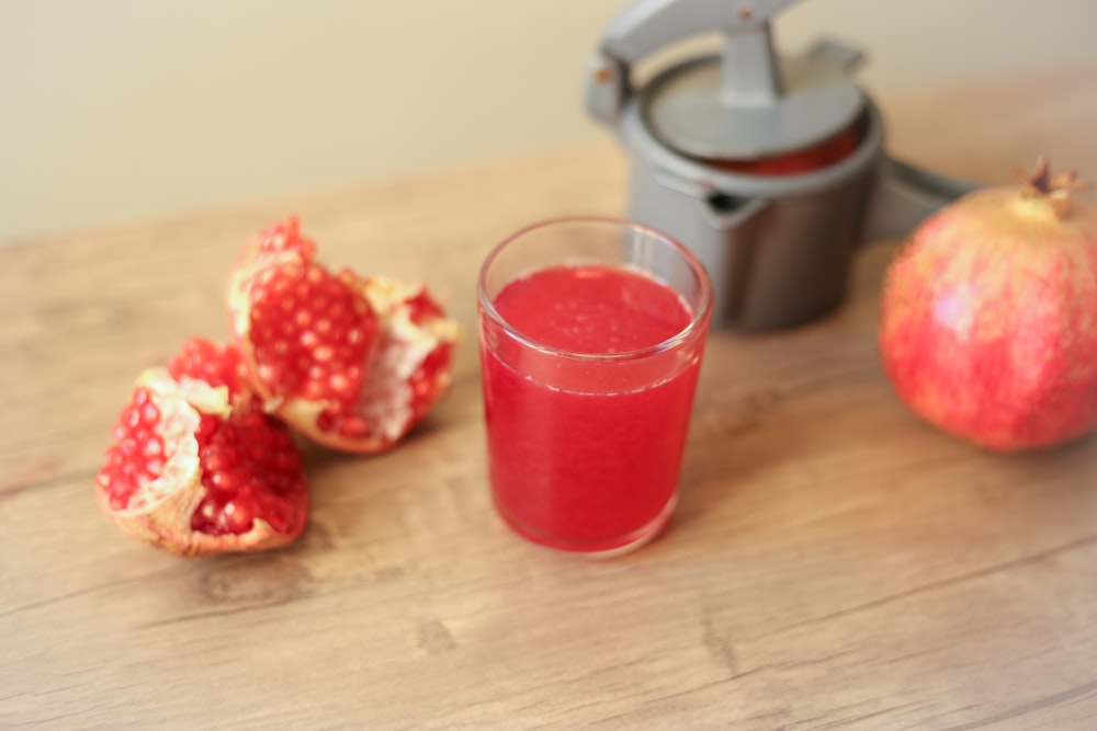 clear drinking glass with red liquid on brown wooden table