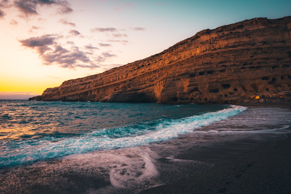 brown rock formation on sea under blue sky during daytime