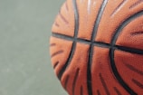 Close-up of a basketball player dribbling on a gym floor.