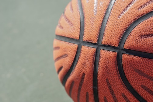Close-up of a basketball player dribbling on a gym floor.
