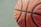 Close-up of a basketball spinning on a finger with a blurred outdoor court background.