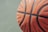 Close-up of a basketball spinning on a finger with a blurred outdoor court background.