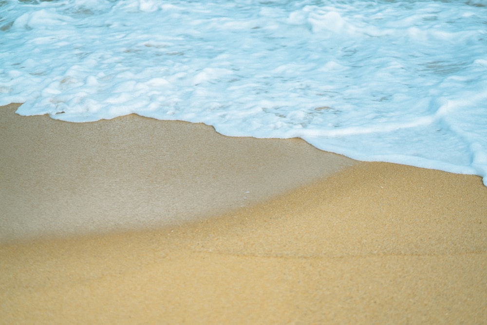 brown sand beside body of water during daytime