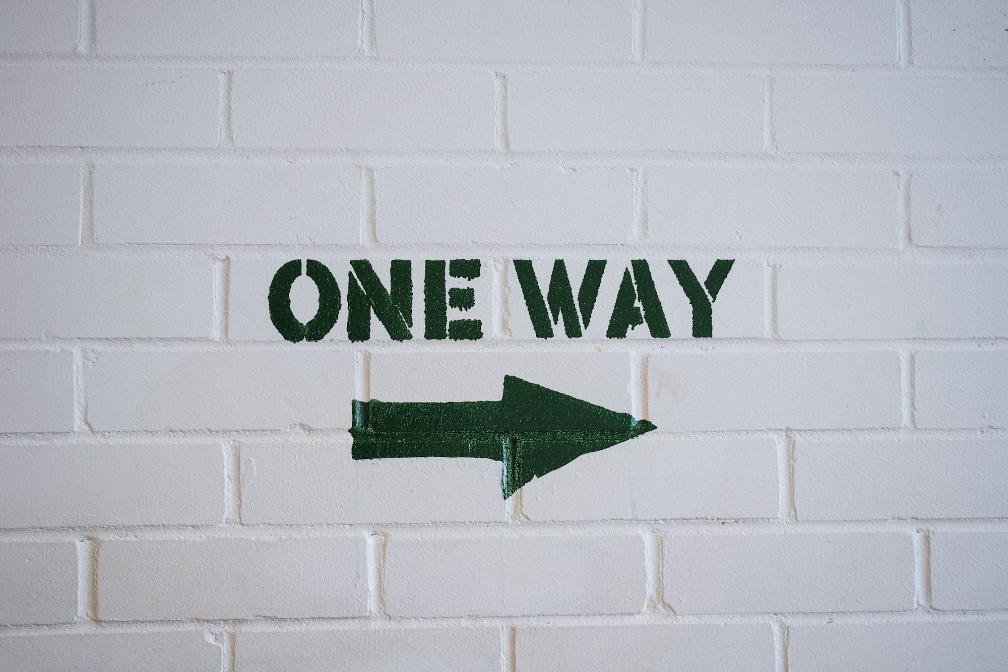 One Way Sign on a white brick wall 