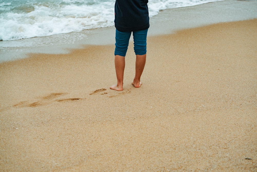 person in black shorts standing on beach during daytime