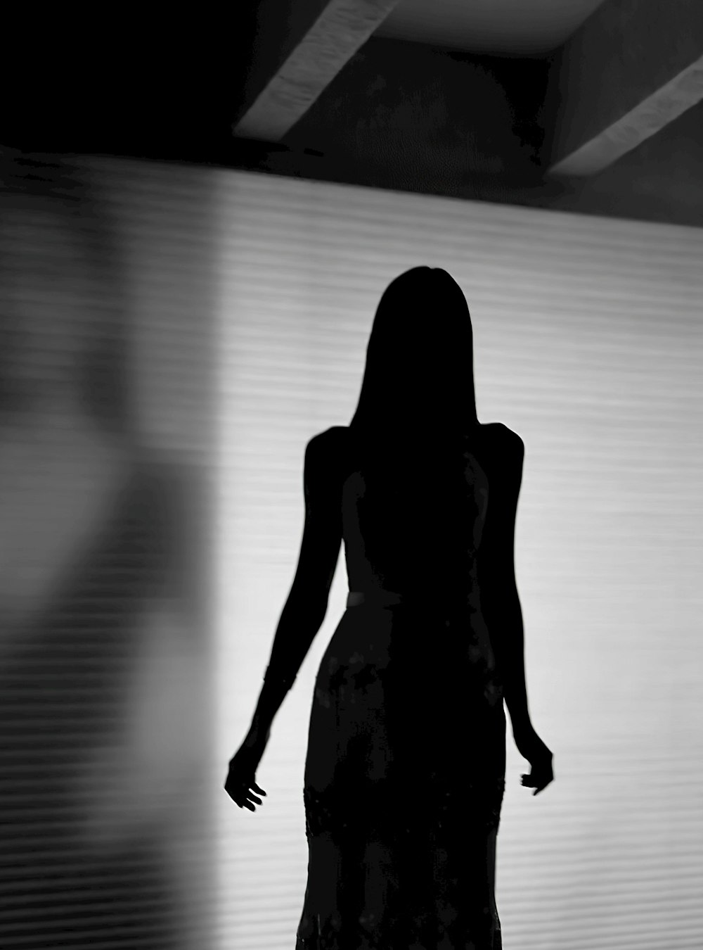 silhouette of woman standing in front of white wall