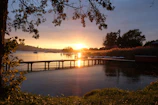 Golden hour light casting long shadows over a quiet lakeside dock.