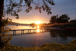 Golden hour light casting long shadows over a quiet lakeside dock.
