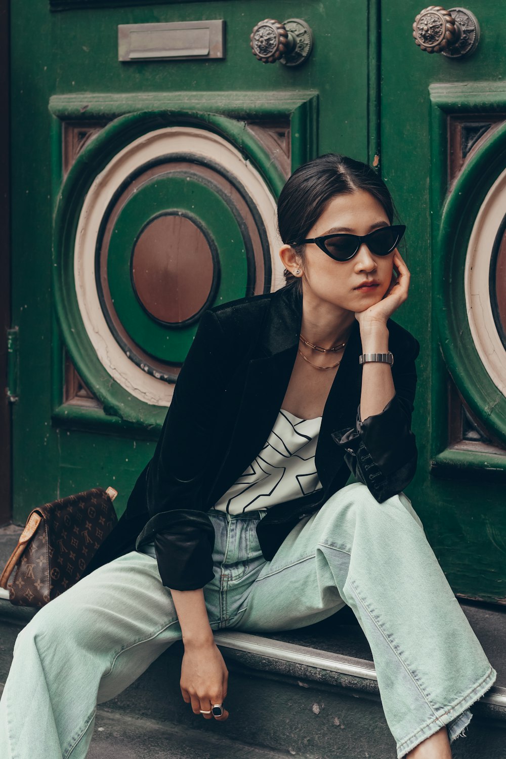 woman in black blazer and white pants sitting on brown wooden bench