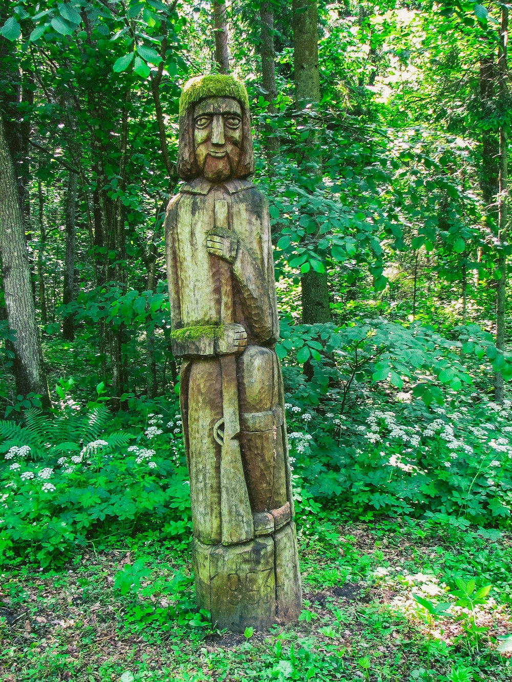 brown wooden statue surrounded by green plants