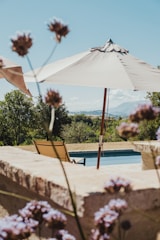 Sunlit serene poolside with stone bastide and linen curtains gently swaying in the breeze.