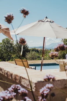 Sunlit serene poolside with stone bastide and linen curtains gently swaying in the breeze.