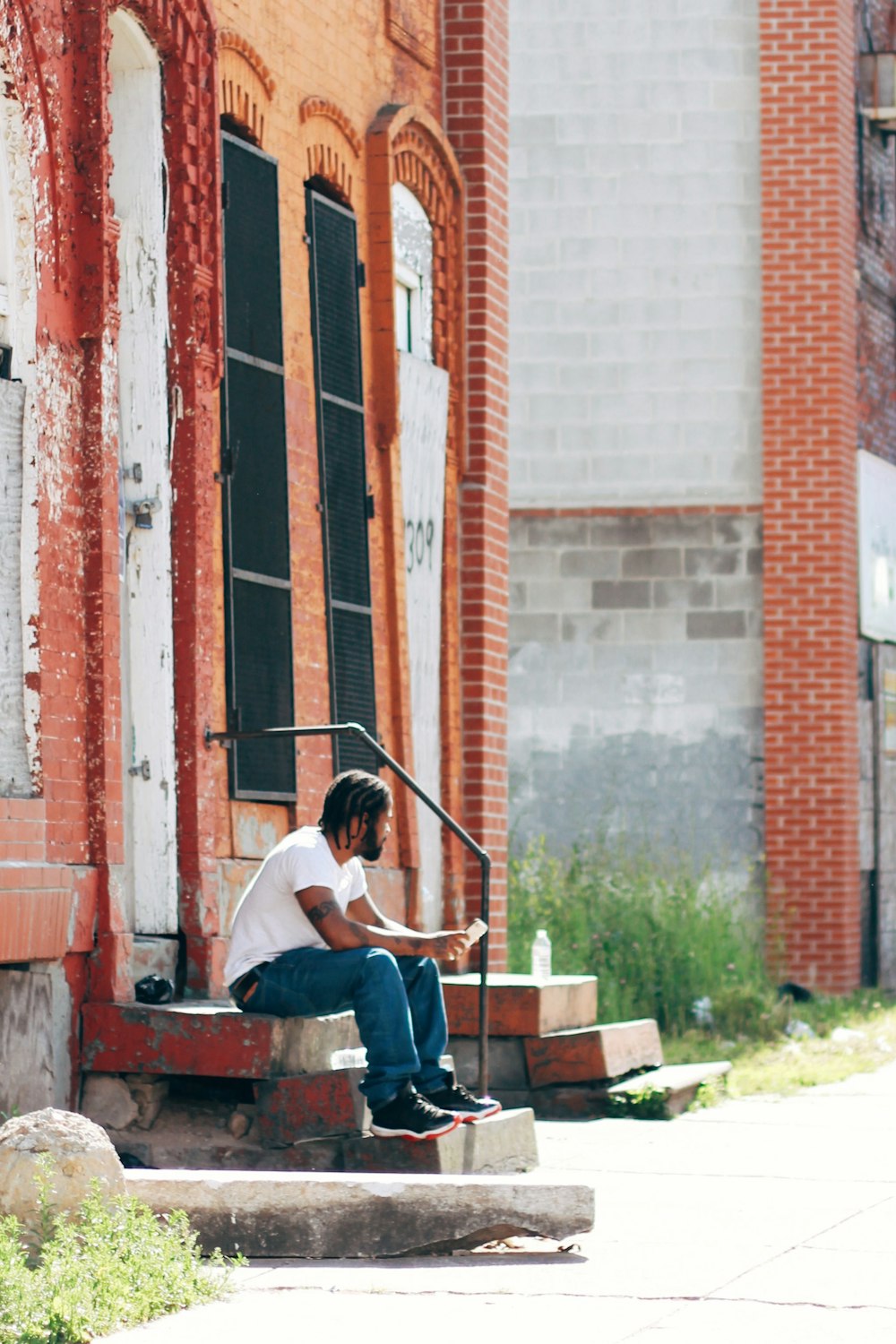 man in white t-shirt sitting on brown wooden bench during daytime