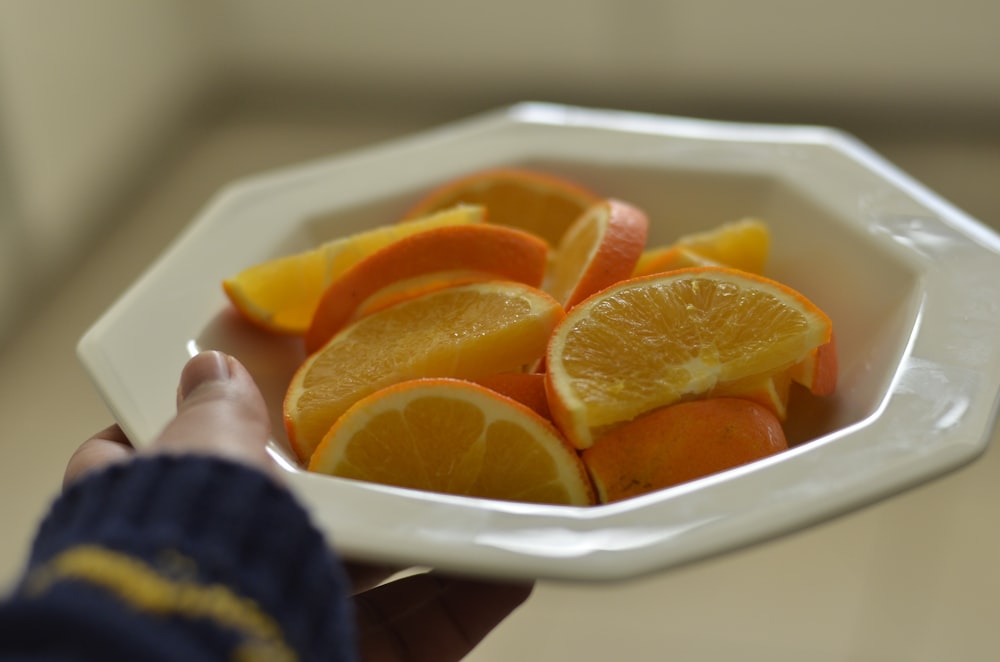 sliced orange fruit on white ceramic tray
