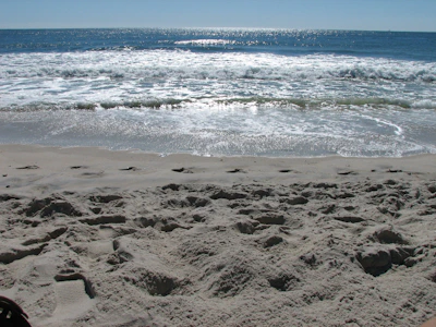 Morning beach scene with soft waves and footprints in the sand near Oceanis guesthouse.