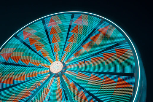A glowing neon spinning wheel with vibrant orange and purple lights in a dark gaming environment.