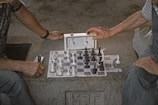 person playing chess on gray concrete floor
