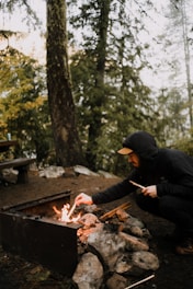 A person practicing fire-starting techniques in a forest setting.