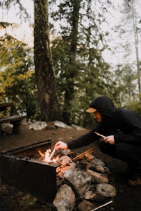 A person practicing fire-starting techniques in a forest setting.