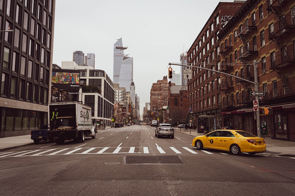 cars on road between high rise buildings during daytime